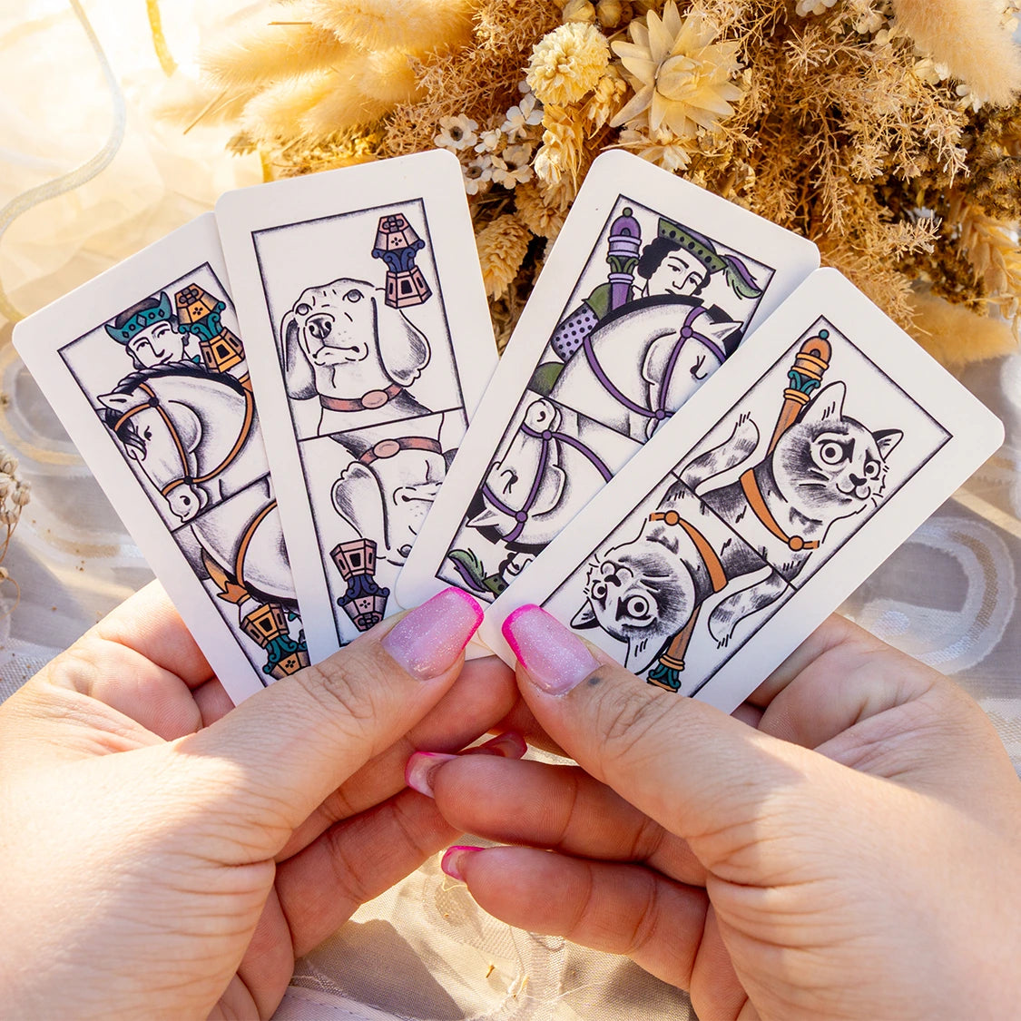 Quattro carte trevisane con Re e Regine, tenute in mano davanti ai fiori secchi