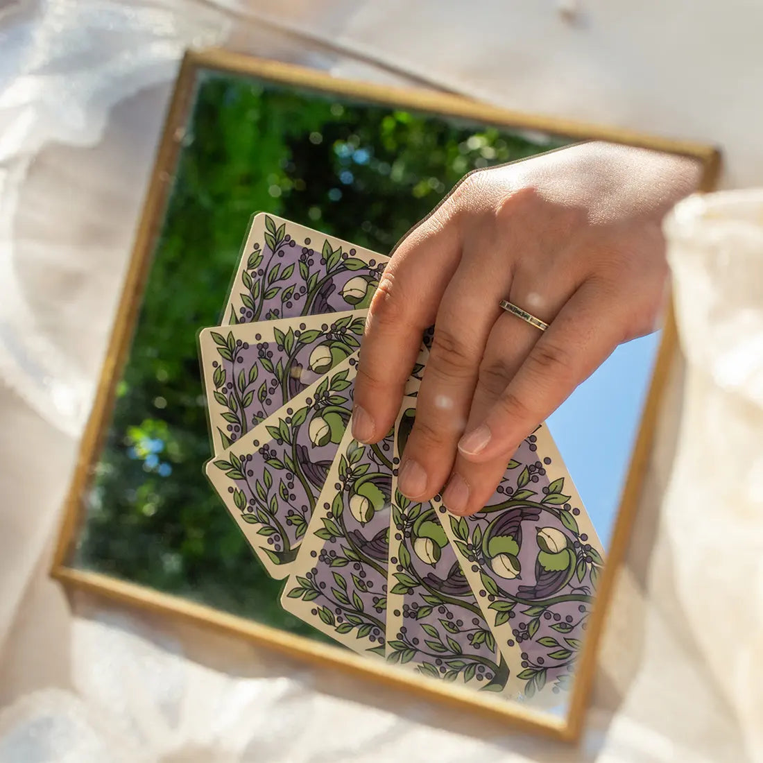 una mano dispone le carte dentro una cornice dorata